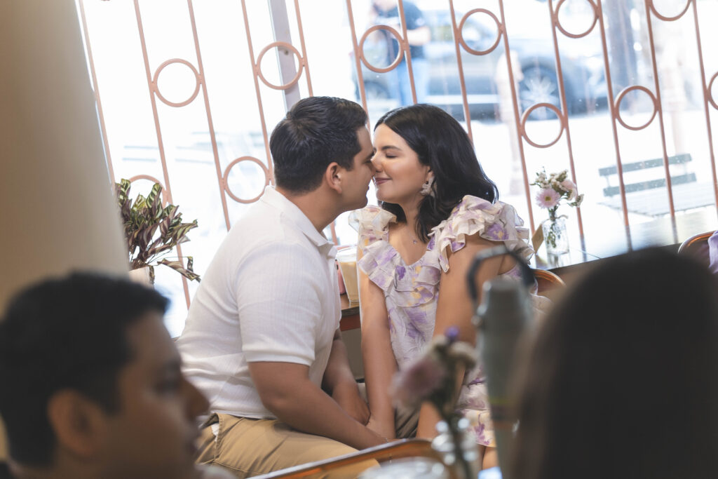 Edisson y Dania: Una sesión previa llena de amor en el corazón de Mexicali | Fotografía y Video en Mexicali | 3 | Los mejores fotógrafos y videógrafos en Mexicali Beso espontáneo de pareja en Sonico Coffee, Mexicali. Sesión previa captada por fotógrafos especializados en bodas, quinceañeras y sesiones económicas express. Calidad garantizada por LosFull.com. Title: Captura íntima en café de Mexicali | Sesión previa para invitación digital de boda